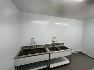 Empty washroom with stainless steel sinks before pipework and hose point installation at a manufacturing facility in Nottingham.